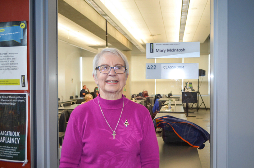 donor smiling while standing beside a classroom dedicated to the memory of mary mcintosh