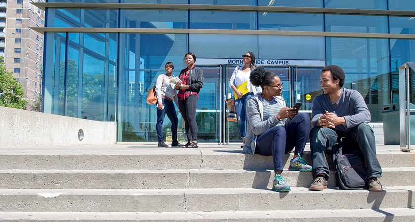 centennial college students smiling while sitting outside on the morningside campus steps talking
