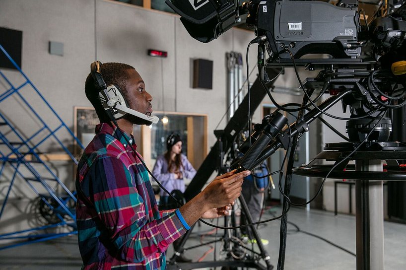 broadcasting student using a camera in a professional studio
