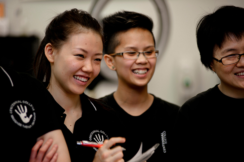 centennial college massage therapy students smiling while taking notes and listening to an instructor