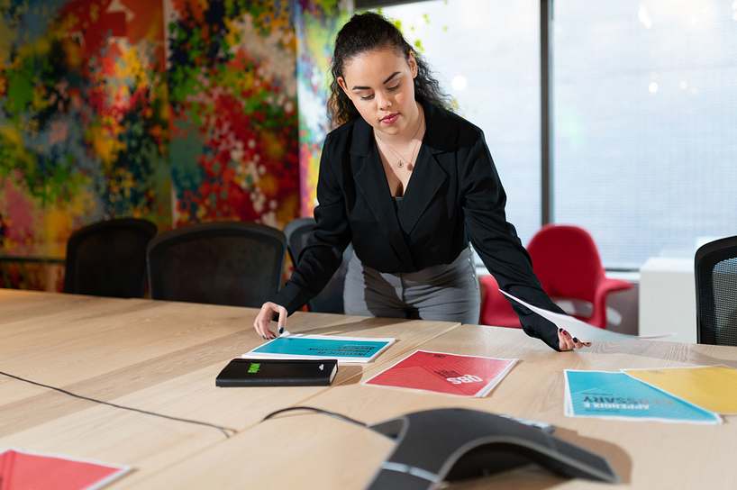 centennial college advertising student layout out various ad mock ups on a table in a boardroom
