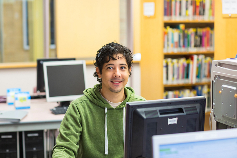 A male student looking for college resources on a computer