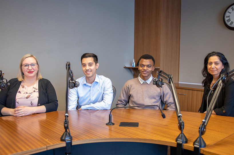 A group of international students and the podcast host sitting behind a desk