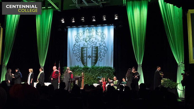 picture of the centennial college convocation stage with graduates walking across shaking hands with faculty