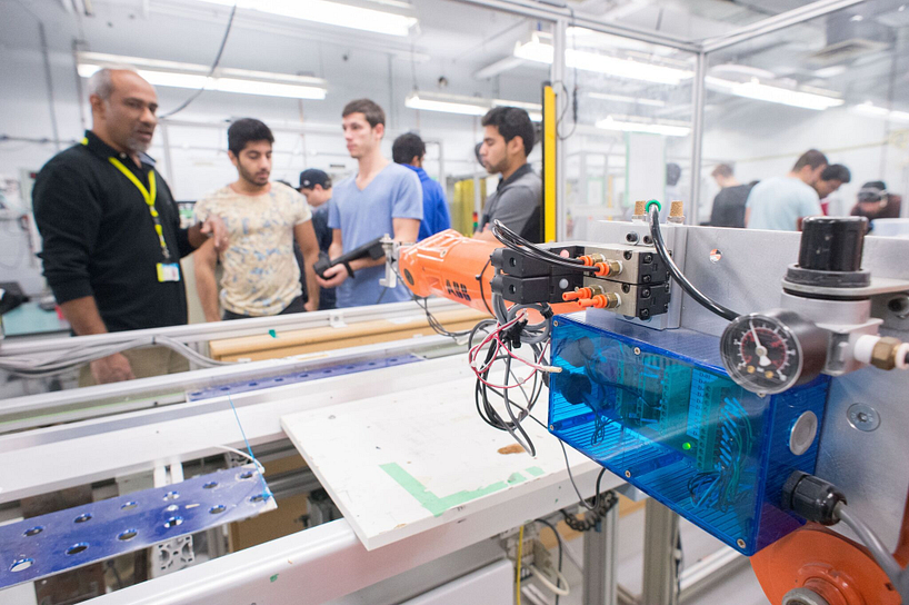 centennial college students and instructor showing a robotic arm