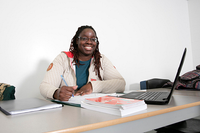 A female Centennial College student sitting at a desk with her computer