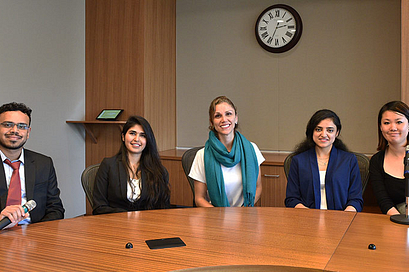 A group of international students and the podcast host sitting behind a desk
