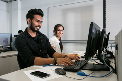 Two students working on their computer in class