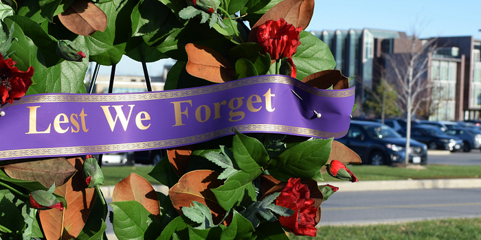picture of a wreath with poppies and a ribbon that reads lest we forget