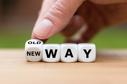 A hand reaching towards dice that has letters that spell New Way
