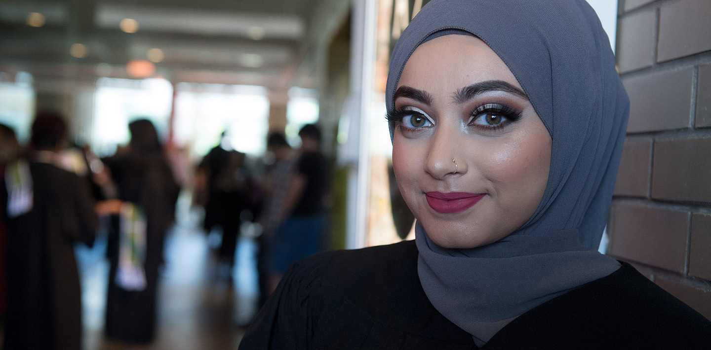picture of a Centennial College graduate smiling looking at the camera at their convocation ceremony