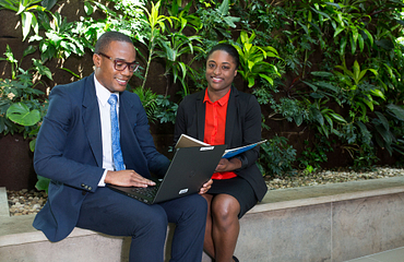 two business people smiling and looking at a computer