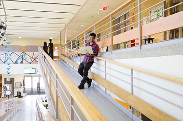 picture of a Centennial College student standing in the Story Arts Centre campus hallway holding a laptop