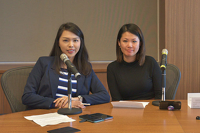 Two female speakers sitting behind a desk with microphones