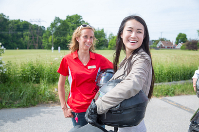 picture of a centennial college motorcycle rider training student smiling holding a helmet with their instructor
