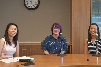 Panel of speakers sitting behind a table with microphones