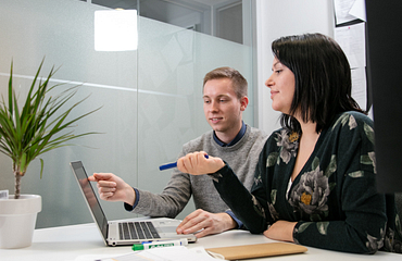 two business people smiling and looking at a computer