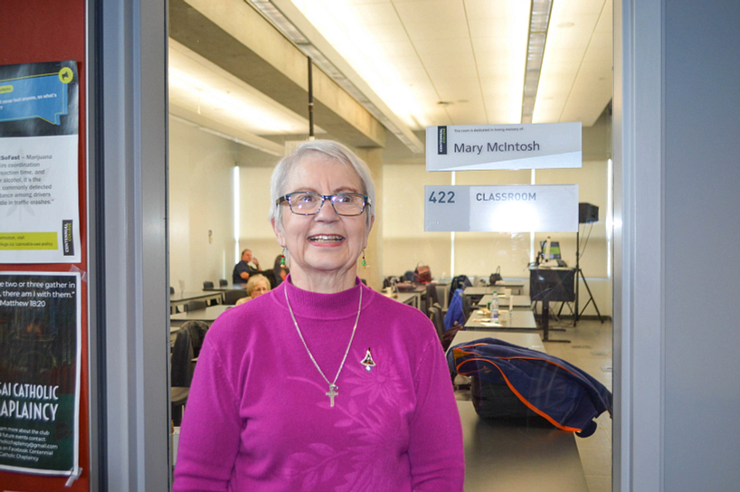 donor smiling while standing beside a classroom dedicated to the memory of mary mcintosh 