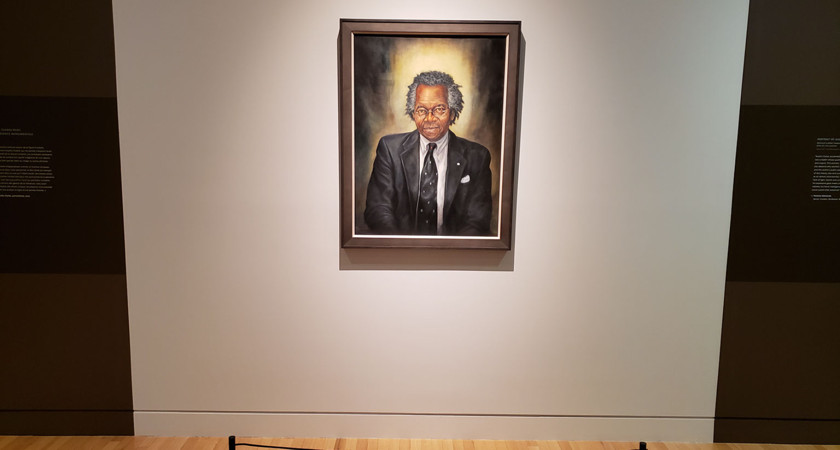 A painted portrait of Austin Clarke by Neville Clarke, hanging on the wall