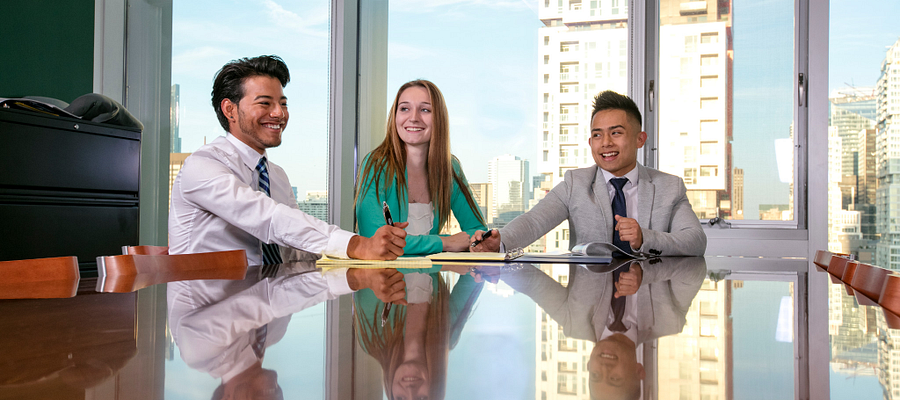 Centennial College students dressed in business professional clothing in a meeting smiling