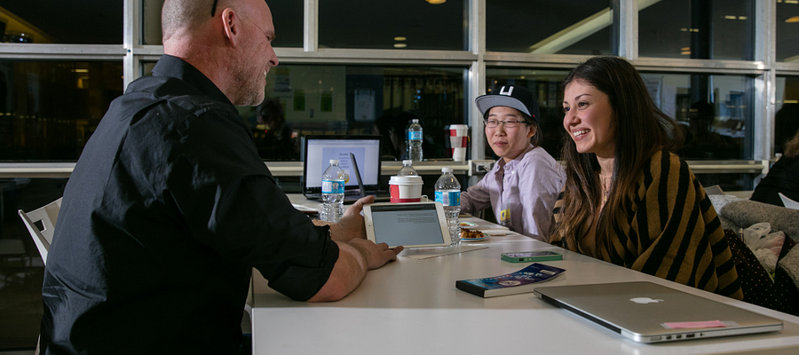 Centennial College students and a potential employer at a table in the Story Arts Centre library smiling and talking
