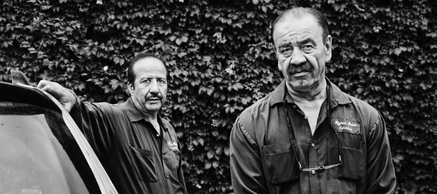 two mechanics standing by a car