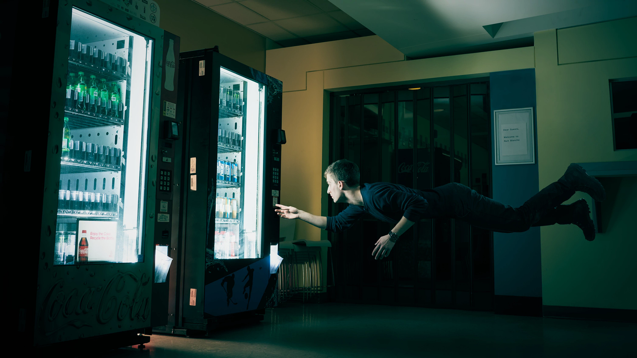 A student levitating horizontally and interacting with a vending machine at Space Oddity - A Nuit Blanche event at Story Arts Centre
