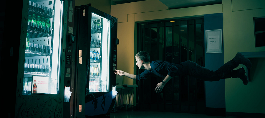 A student levitating horizontally and interacting with a vending machine at Space Oddity - A Nuit Blanche event at Story Arts Centre