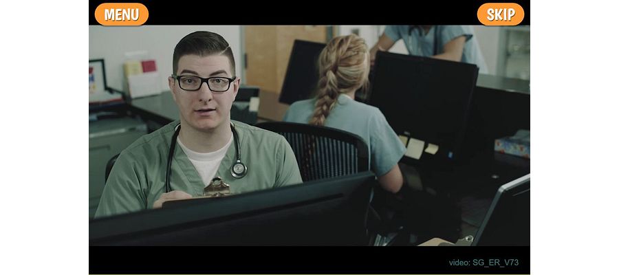 Screenshot of a scene of the Virtual Hospital game that depicts a male nurse wearing scrubs in front of a computer