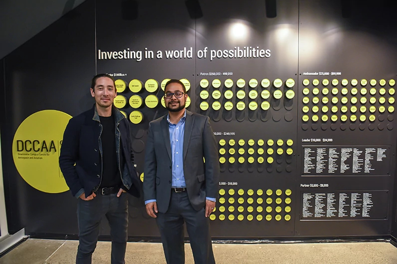 donors smiling while standing by the centennial college downsview campus donor wall