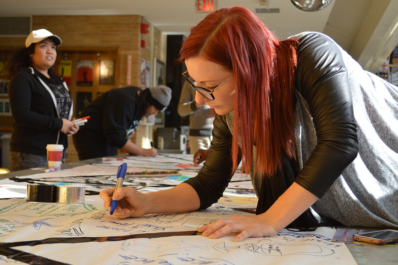 Student writing on a large mural