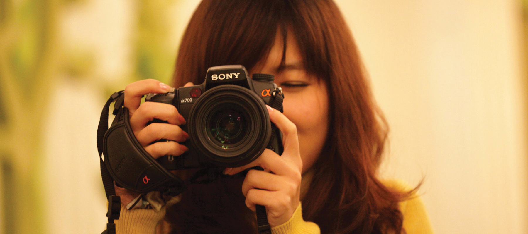 student holding a camera and looking through the viewfinder