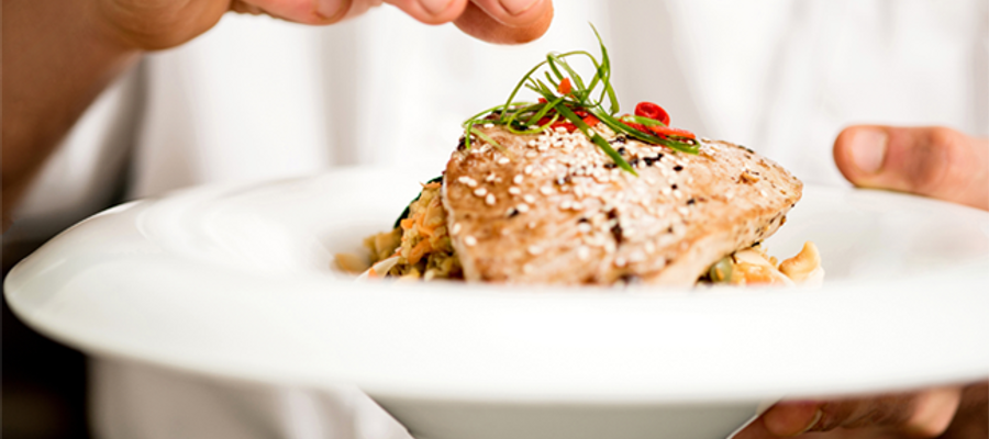 A culinary student showing off his salmon dish on a plate