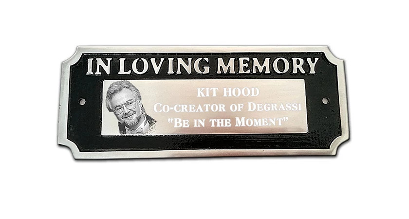 A plaque that says, 'In Loving Memory', Kit Hood, Co-Creator of Degrassi, 'Be In The Moment'