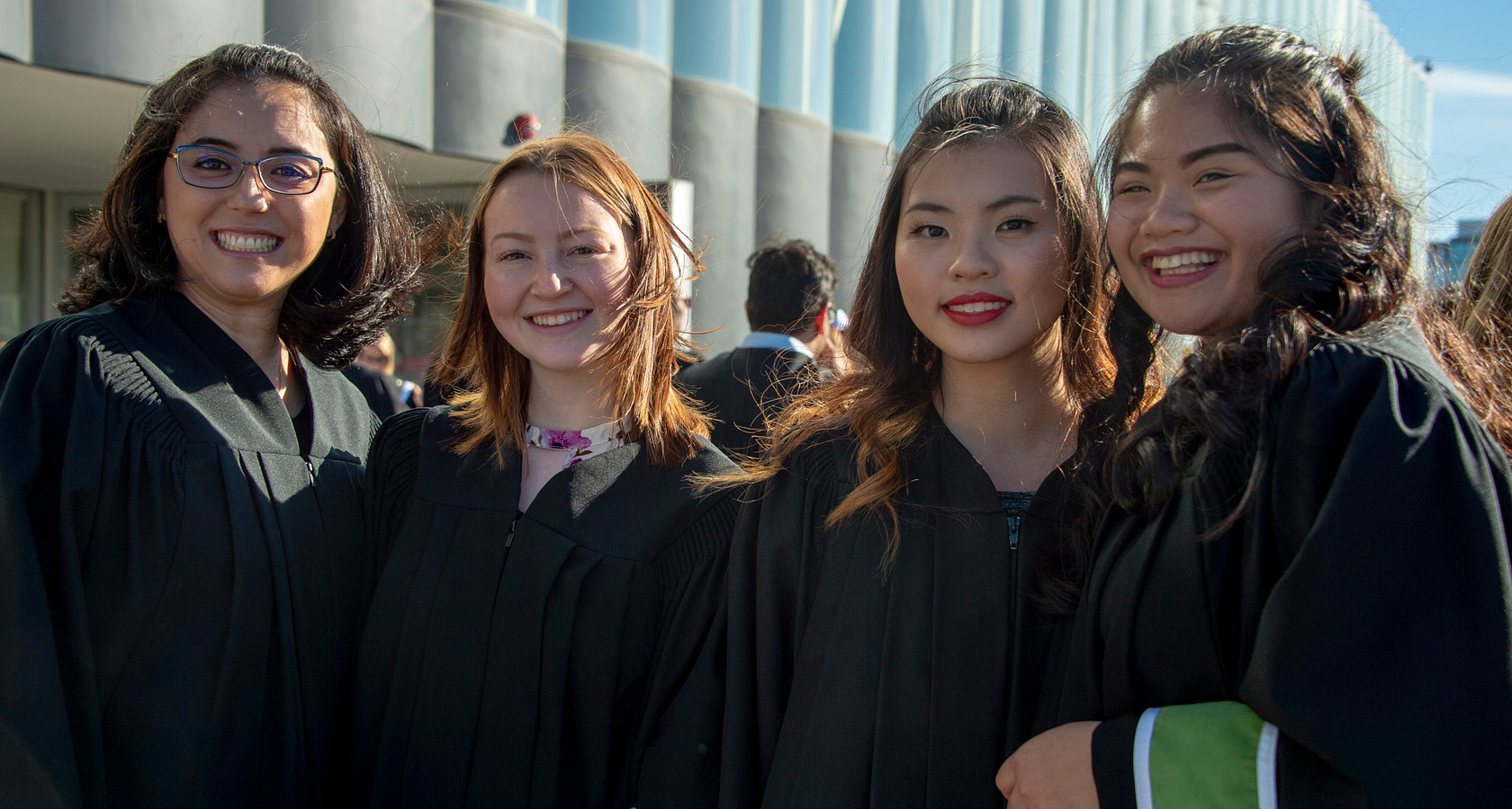 centennial college graduates smiling together at their convocation ceremony standing outside on a sunny day