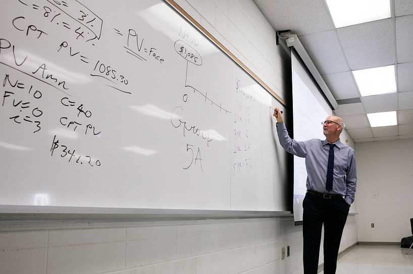 A professor lecturing in front of a white board in class