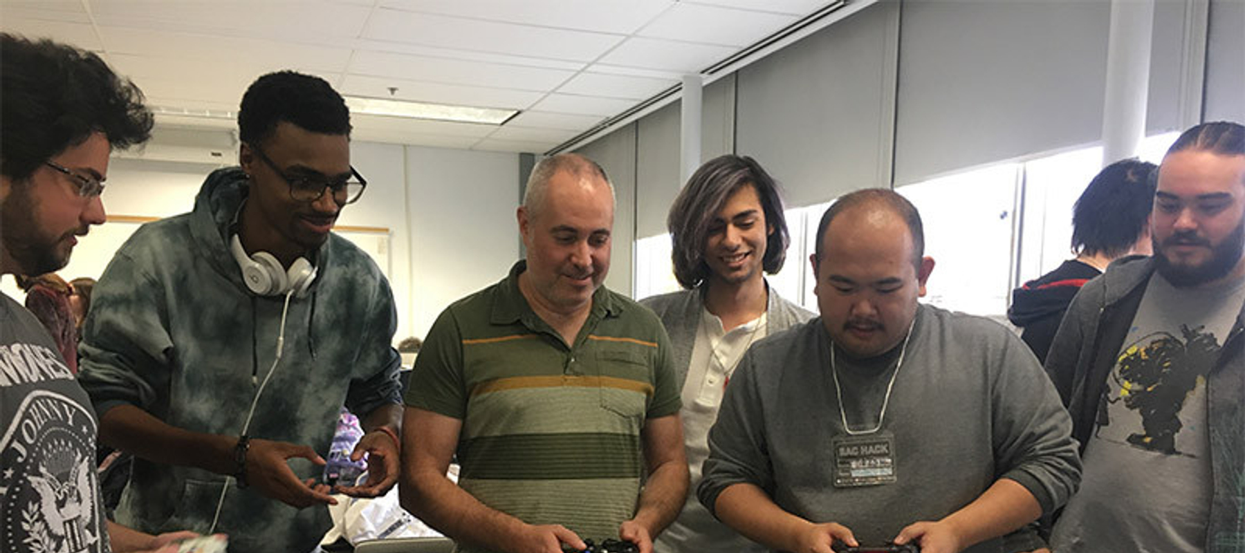 centennial college game development program students and faculty playing a video game with controllers
