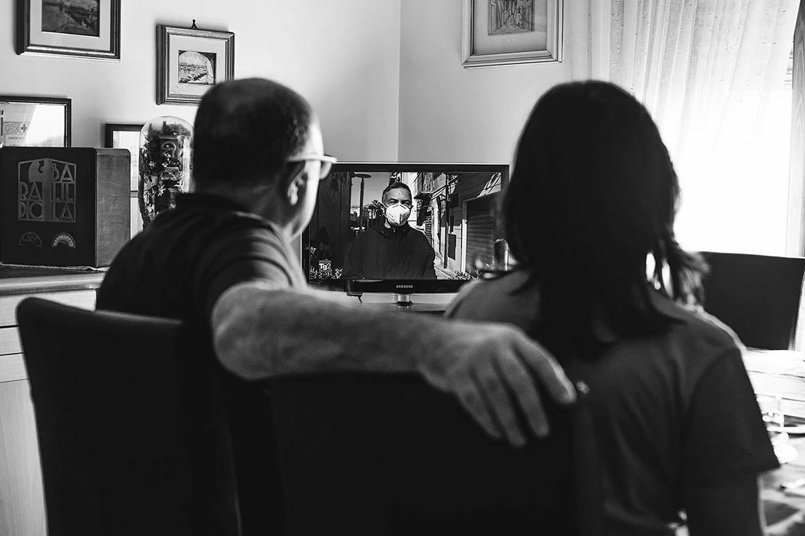 Tobi Asmoucha photography depicting two people sitting on a chair watching television during the COVID-19 pandemic