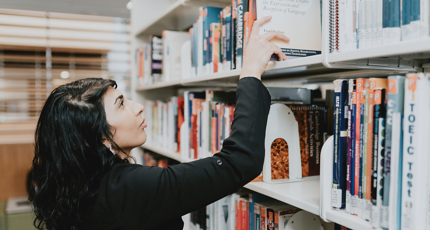 A female student browsing through the books at the college library