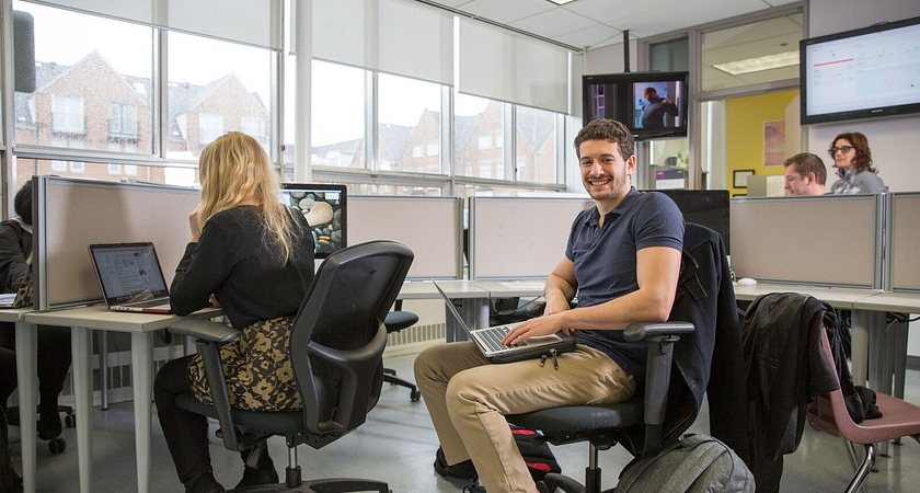 picture of a Centennial College student smiling and working in a computer lab at the Story Arts Centre