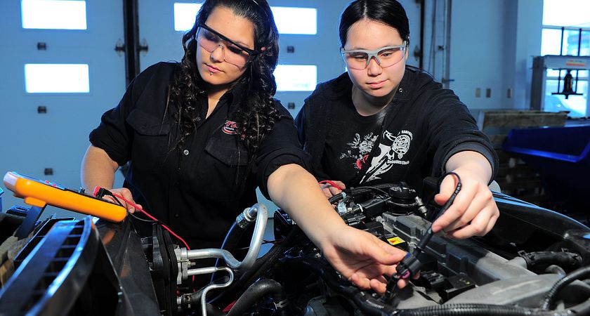 Photo of two female transportation students monitoring a car engine using an analysis tool.